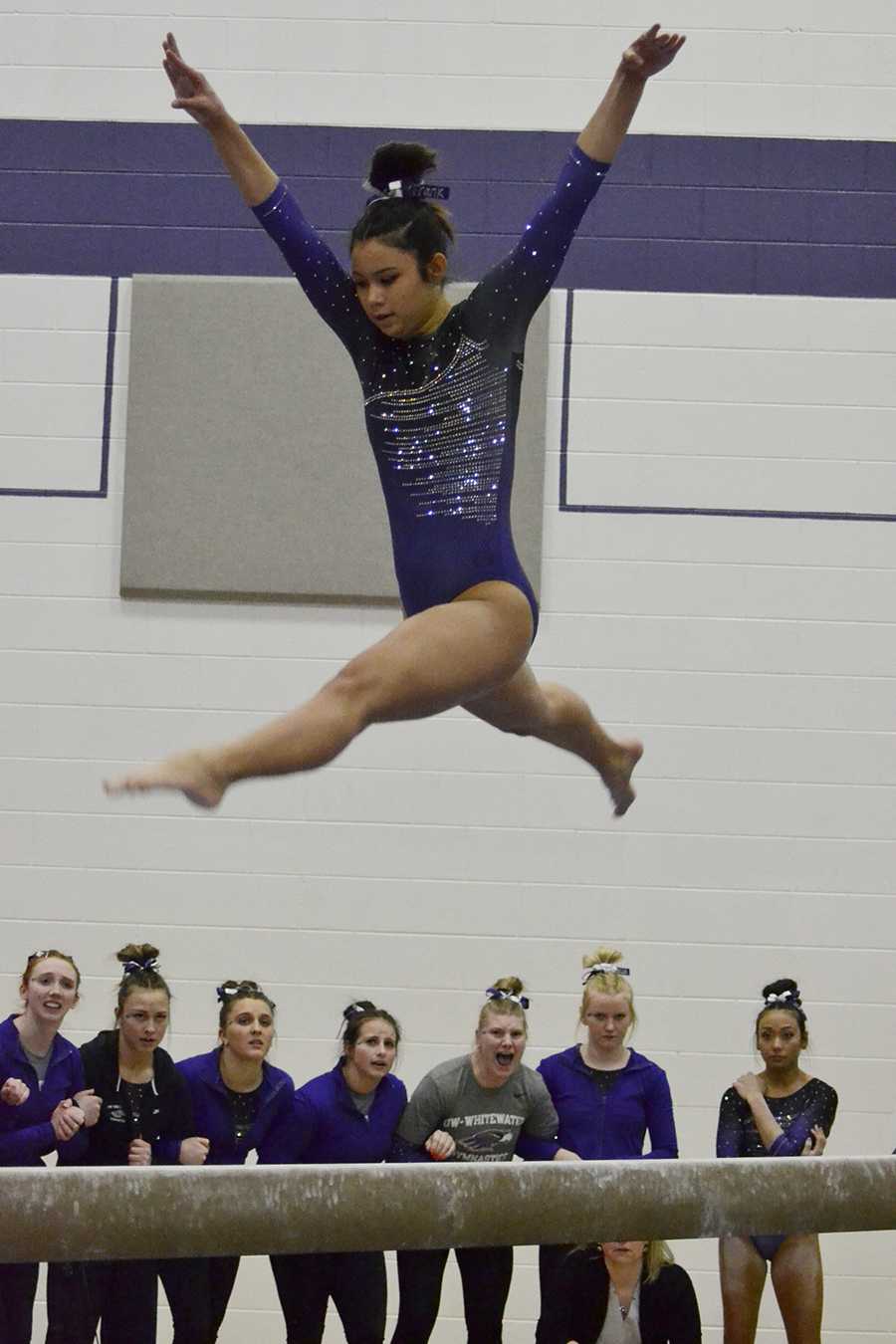 Sophomore Franchesca Hutton leaps in the air during her
balance beam routine as her teammates cheer her on in the March 11 victory against Hamline University. Photo by Sierra High