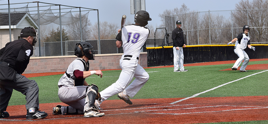 Junior outfielder Brett Krause begins running down the first base line after connecting on a hit as freshman outfielder Matt Wary rounds third base in an April 8 doubleheader vicotry vs. UW-La Crosse. The Warhawks have now won six straight. Photo by Hannah Jewell