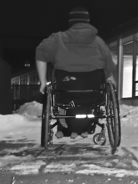 Junior Rachel Nepper navigates the snowy sidewalk  in front of Roseman Hall in her wheelchair.