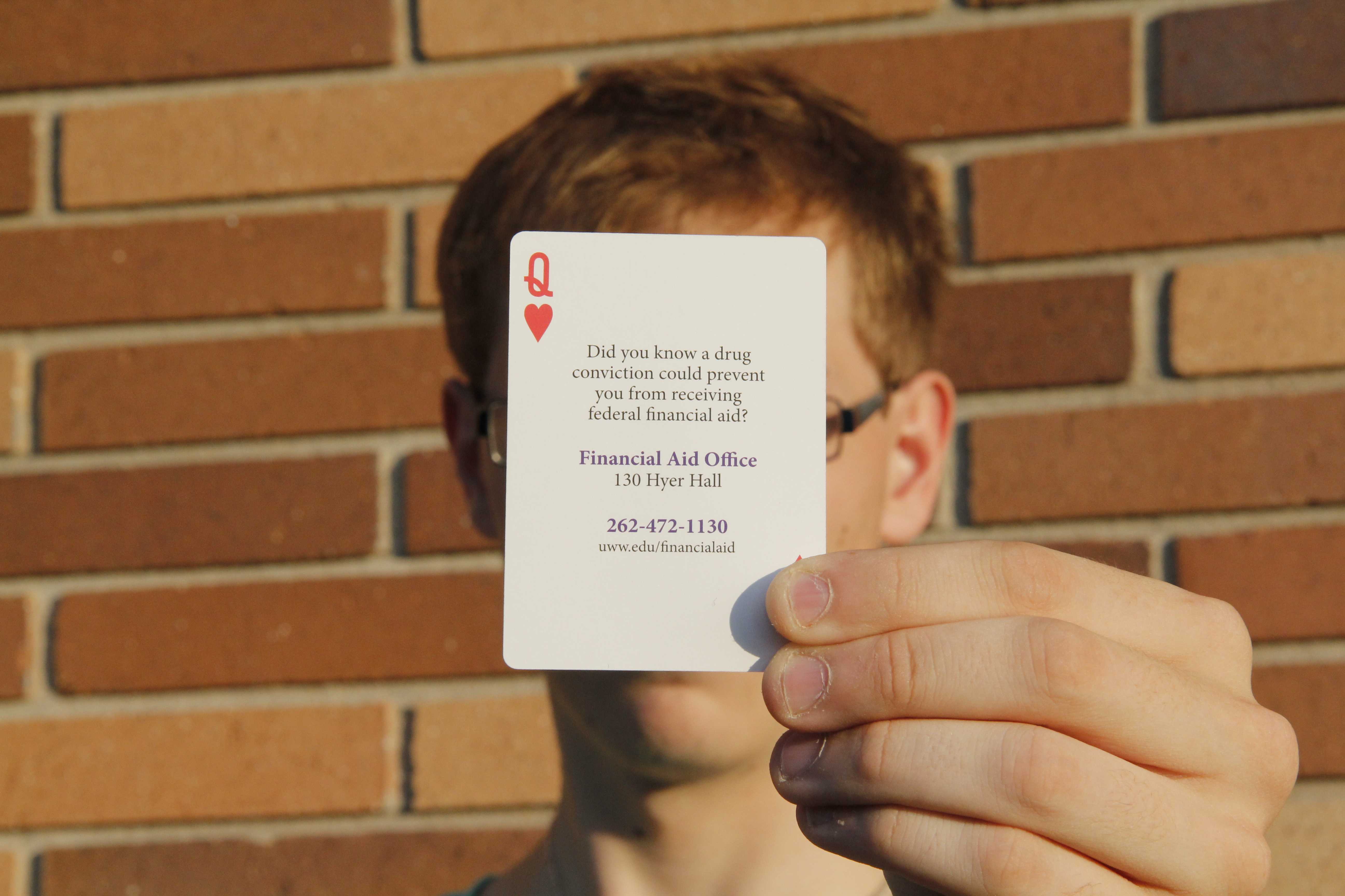 Photo by Sean Kirkby: A former University of Wisconsin-Whitewater student poses with a playing card distributed by the campus warning of the penalties of a drug conviction. The student, who requested anonymity because he is looking for a job, sold drugs to another student on campus who was a confidential informant.