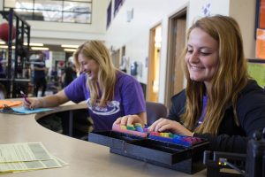 Seniors Glynis Albue and Christine Panella work the front desk at the Williams Center weight room.