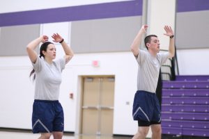 Brienna Herdrich and Justin Nemoir perform jumping jacks during physical training. 