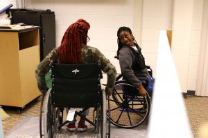 Sophomore Alice Gilliam speaks with another group member as they attempt to roll over gravel and wooden boards with wheelchairs at Boxes and Walls on Oct. 12. Photo by Kimberly Wethal.