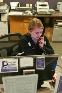 Sophomore Emily Schwartz answers the phone as a desk attendant in the University Center. The number of hours students can work on campus decreased from 30 a week to 25. The change in weekly hours is due in part to the Affordable Care Act, which forced UW-Whitewater’s Human Resources Department to even out the full-time hours students work during breaks and the rest of the year. Photo by Kimberly Wethal.