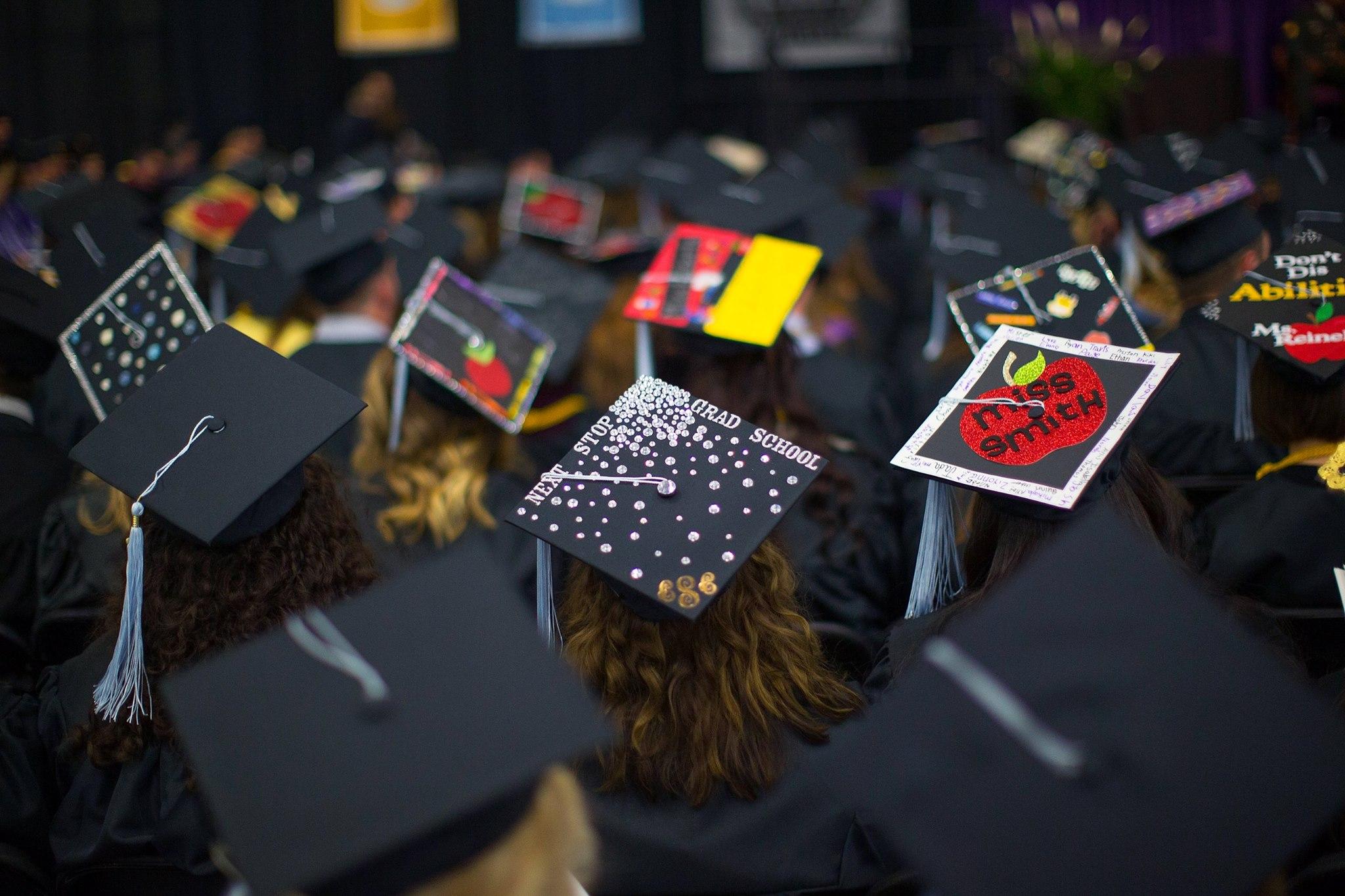Students’ decorative graduation caps sit on display during the Fall 2016 commencement ceremony. Changes in this year’s commencement activities are due to the large crowds from students and families.