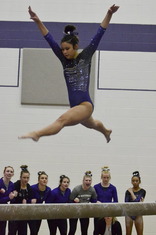 Sophomore Franchesca Hutton leaps in the air during her 
balance beam routine as her teammates cheer her on in the March 11 victory against Hamline University. Photo by Sierra High