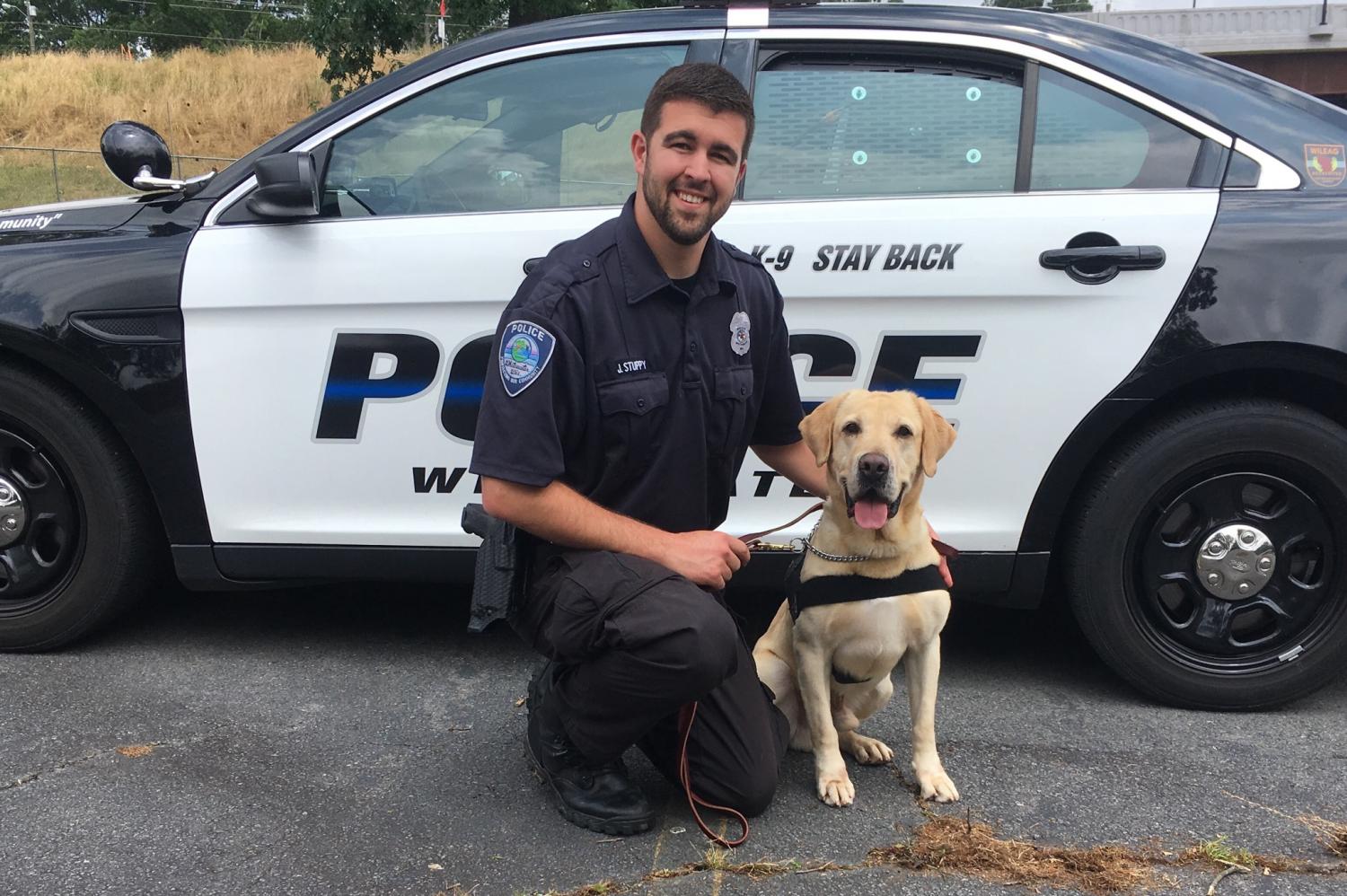 Officer and 2017 University of Wisconsin-Whitewater alumnus Justin Stuppy
crouches with his K-9, Ruso, a yellow Labrador retriever.