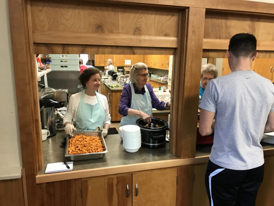 olunteers for First Methodist Church serve hot food to students during a free lunch event. The church has been dishing out hot meals to students and community members for nearly 20 years. 