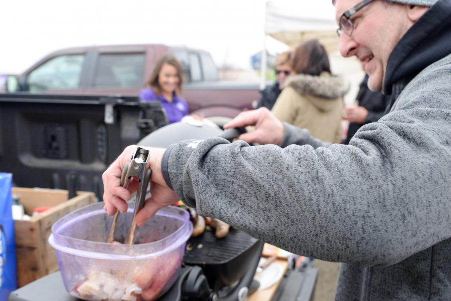 A Warhawk alum grabs a hot dog to throw on the grill while tailgating before a football game. 