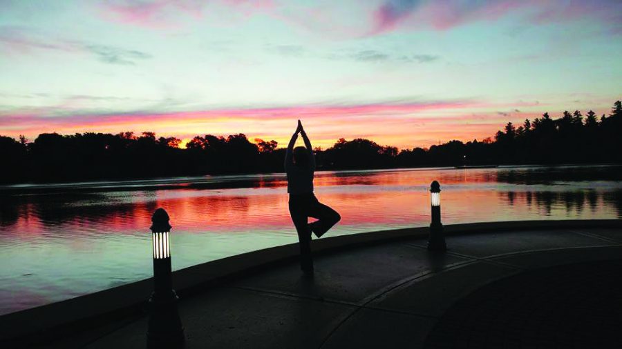A woman practices and watches the sun rise over Cravath Lake during the morning yoga class.