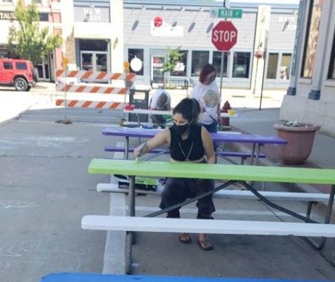 Volunteers paint picnic tables for a new outdoor eating area in downtown Whitewater open through Oct. 31.