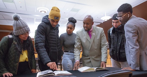 UW-Whitewater students look at high school yearbooks brought to a campus Diversity Forum program by Chief Equity, Diversity and Inclusion Officer Kenny Yarbrough. From left are Jessica Aldama, a human resources management major from Algoma, Purcell Pearson, a psychology major from Milwaukee, Destiny Tillman, a sociology major from Milwaukee, Yarbrough, and Jonny Carbajal and DyQuan Gipson, both accounting majors from Milwaukee, on Wednesday, Feb. 26, 2020. (UW-Whitewater photo/Craig Schreiner)