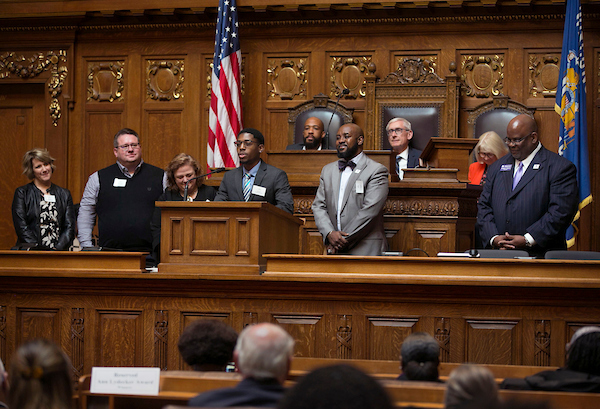 Accounting and management double major Rasheed Goodman speaks on behalf of the Little Scholars mentoring program with the delegation from UW-Whitewater. In the background are from left, Wisconsin Lt. Gov. Mandela Barnes, Gov. Tony Evers and Evers wife Kathy Evers. UW-Whitewater received two statewide awards  an Outstanding Achievement Commendation for the Little Scholars mentoring program and the first annual Lifetime of Service award presented to Dr. Roger Pulliam  at the Ann Lydecker Educational Diversity Award ceremony Thursday, Oct. 24, 2019, in the State Assembly chamber at the Capitol in Madison, Wis. The awards are given annually by the State Council on Affirmative Action.  (UW-Whitewater photo/Craig Schreiner)