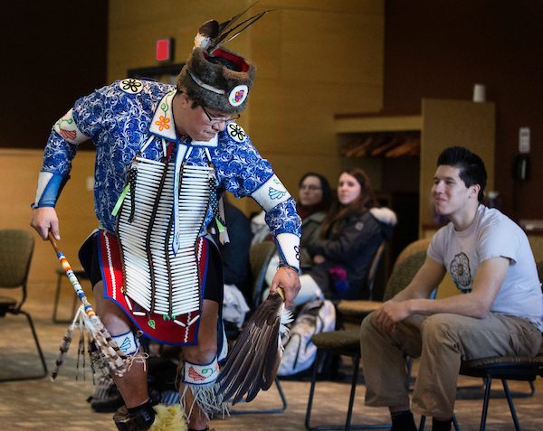 Mino-Giizhik DeBungie performs a hunting dance watched by students including UW-Whitewater criminology major Cody Wing, who is president of the Native American Cultural Awareness Association. Debungie is a member of the Red Cliff Band of Lake Superior Chippewa and Wing is a member of the Bad River Band of Lake Superior Chippewa. Six members of the Red Cliff Band of Lake Superior Chippewa from Bayfield County in northern Wisconsin visited UW-Whitewater to talk with students about native culture and perform traditional dances, drumming and singing. Classes in restorative justice, American Indian studies and dance participated through the afternoon on Wednesday, March 6, 2019. (UW-Whitewater photo/Craig Schreiner)