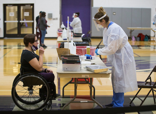 UW-Whitewater head womens wheelchair basketball coach Christina Schwab, left, collects a sample for tester Rebecca Hasler. Students, staff and community members came to the Williams Center on the UW-Whitewater campus for the first day of a federal COVID-19 testing program open to the community in Kris Russell Volleyball Arena, on Monday, Nov. 9, 2020. (UW-Whitewater photo/Craig Schreiner)