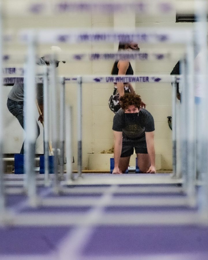 Seen through rows of track hurdles, Jack McGinn prepares to compete during an intrasquad
track & field meet inside the Kachel Fieldhouse on Saturday Jan. 23.