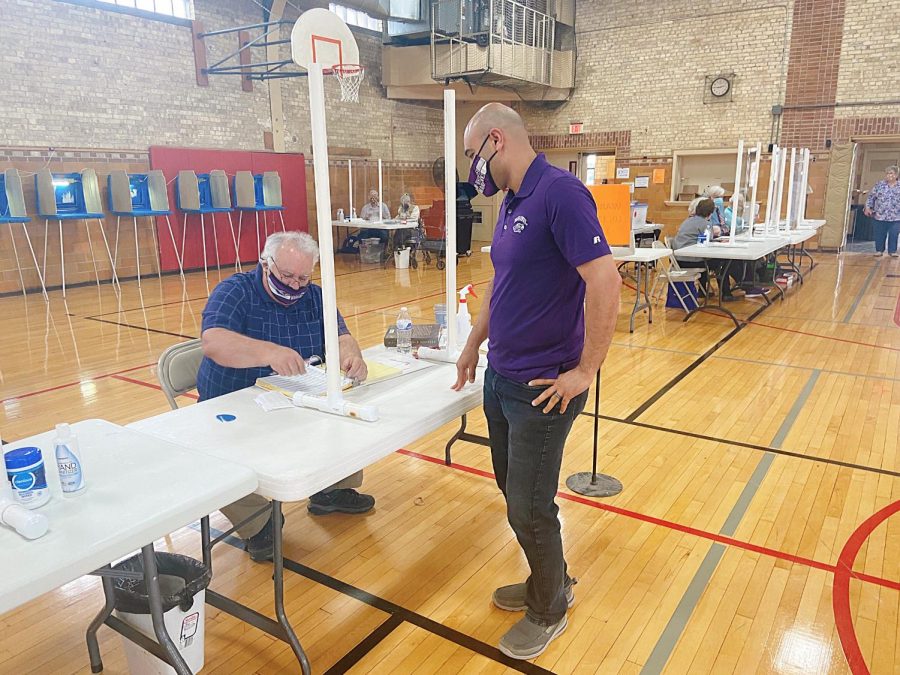 Jalal Nawash the Director of Undergraduate Research Programs on campus receives his ballot to vote at the Whitewater Armory Gym, Tuesday, April 6th.