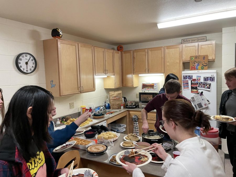UW-Whitewater students gathering around a table of food while enjoying a Friendsgiving
