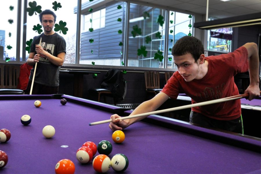 Sophomore Caleb Gough aims to hit the cue ball against a striped ball during a game of pool with junior Steve Tbojevic in the Warhawk Alley.
