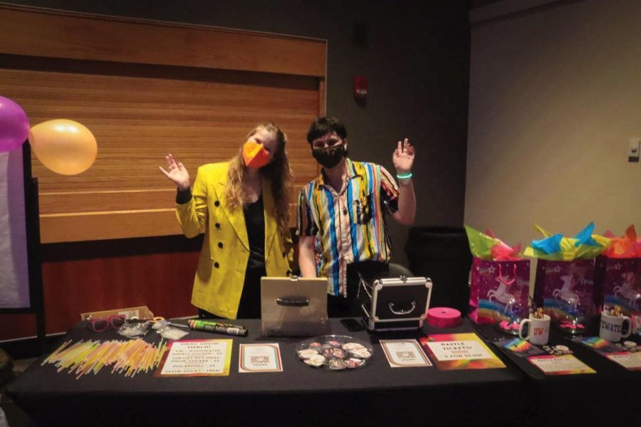 Megan Kaiser (left) and Miles Duckert help work the gift basket and merchandise table during IMPACTs 13th annual drag show in person at the James R. Connor University Center Thursday night April 7, 2022.