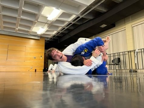 A UW-W Brazilian Jiu Jitsu Club member fights skillfully on the floor mat against his opponent.