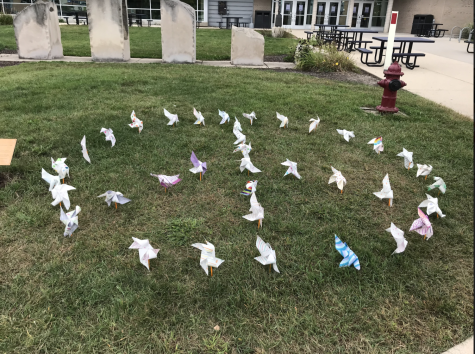 Psychology club arranges pinwheels in a peace sign on the front lawn of the University Center.