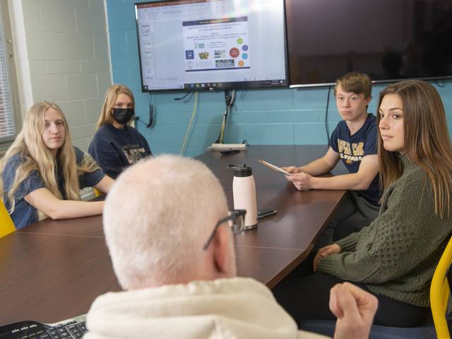 UWEC students, from left, Abby McCullough, Morgan Delzan, Luke Plagens and Annabelle Howat work on a research presentation with Dr. Eric Jamelski, a professor in economics.