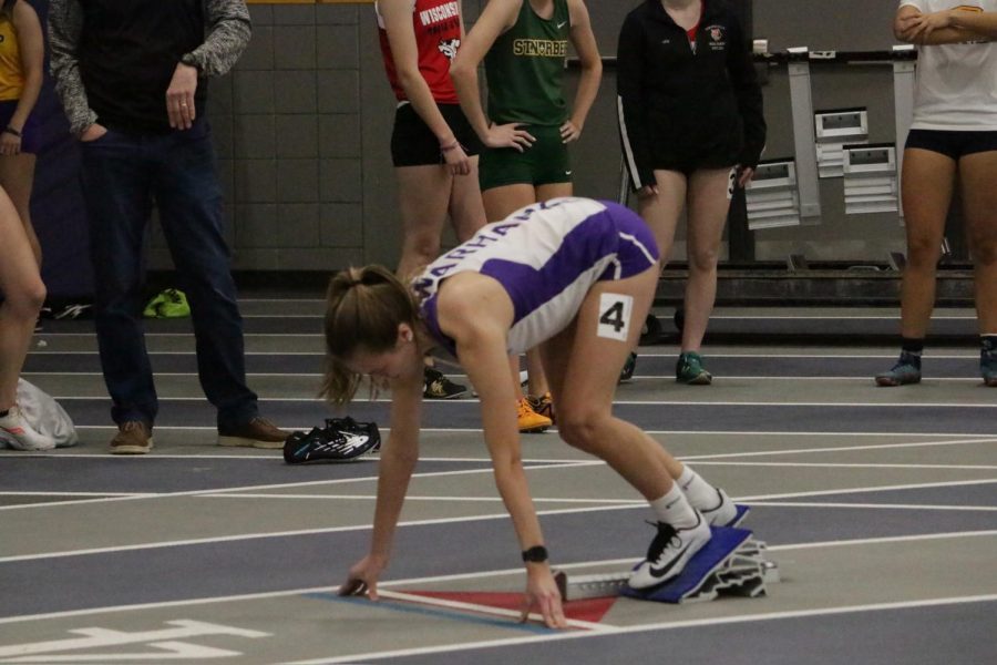 tion: Katie McNamara sets up in the blocks and prepares to race at an indoor track event 