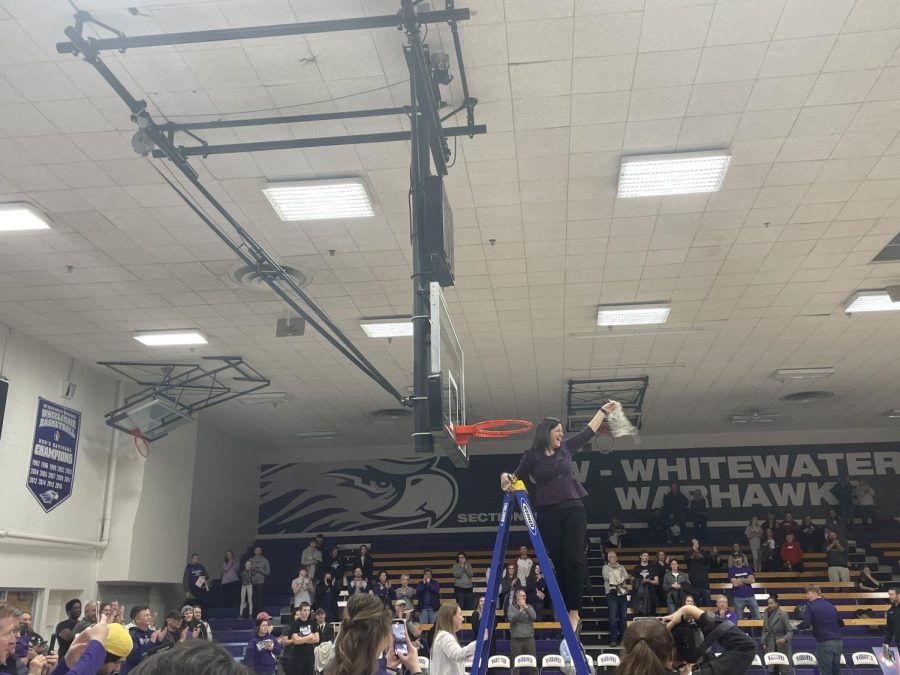Head coach Keri Carollo cuts down the net and waves it to her team after winning her third WIAC tournament championship in her 21st season as the Warhawks head coach
