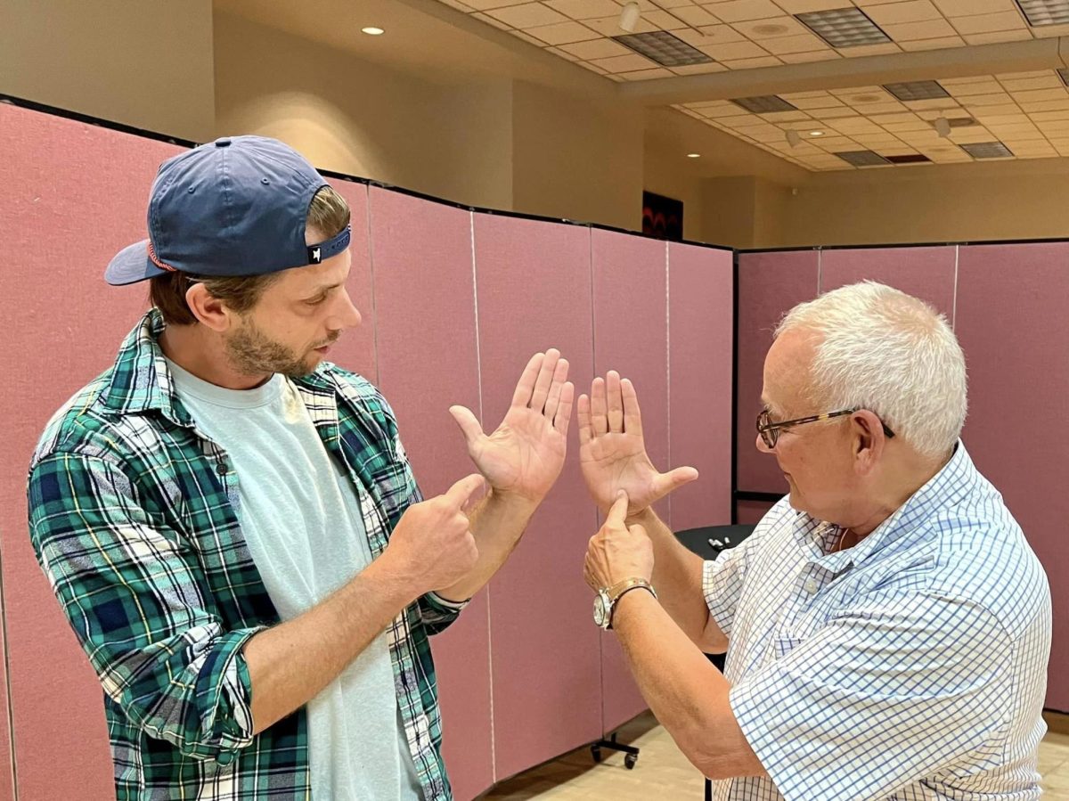 Comedian Charlie Berens and Whitewater realtor Robert Sivek use their hands to discuss Wisconsin geography before Berens performed Friday, Sept. 8 at the Young Auditorium. 