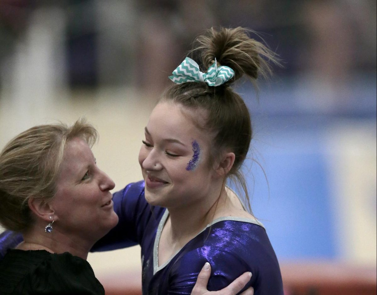 The Warhawks’ Kara Welsh, right, is hugged by Jennifer Regan, head gymnastics coach, after competing on the vault against Hamline University on Saturday, Feb. 24, 2023.