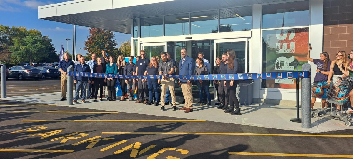  Employees of Aldi gather outside the new store in Whitewater to cut  the ribbon to officially open the store to the public Sept. 19 2024.