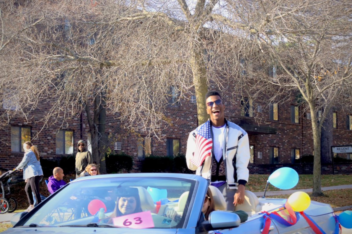 Solomon IV Foley laughs and waves an American flag as his float passes through Main Street during the Homecoming parade, Saturday morning, November 2, 2024.