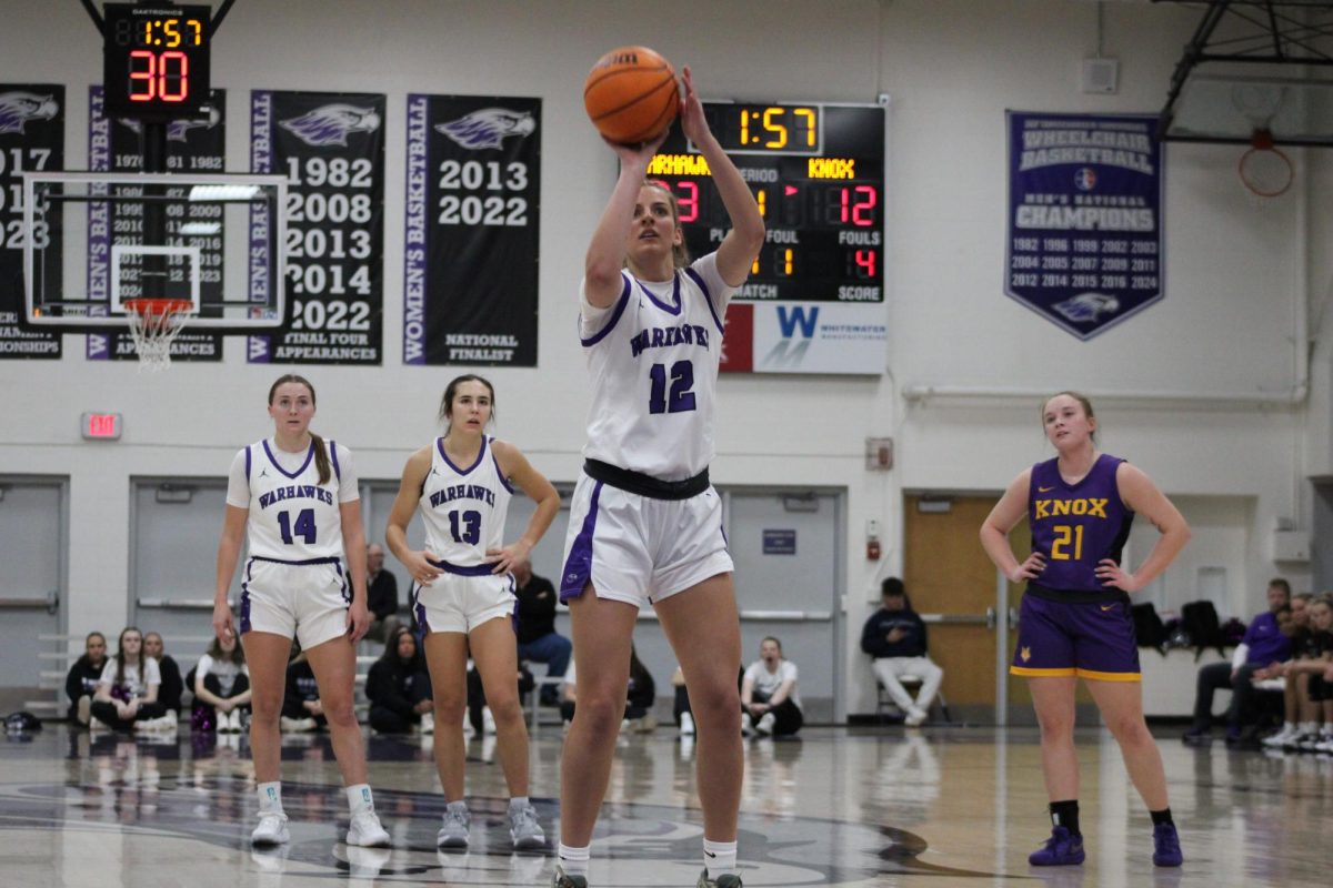 Mallory Oloffson (12) shooting a free throw against Knox College at Kachel Gymnasium on Saturday, Dec. 7. The Warhawks shot 17-19 from the free throw line en eoute to their 91-49 defeat over the Prairie Fire. (Left to right: Sophomore guard Bri McCurdy [14], senior guard Kacie Carollo [13], Oloffson, Knox College sophomore guard Leah Schoonover [21])