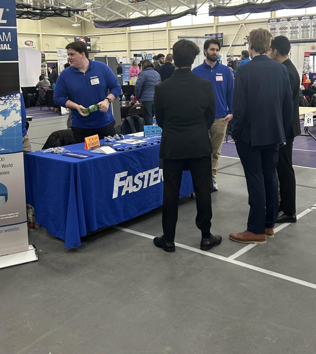 A trio of students gather around the Fastenal booth to ask questions and listen to the speaker, February 12, 2025.