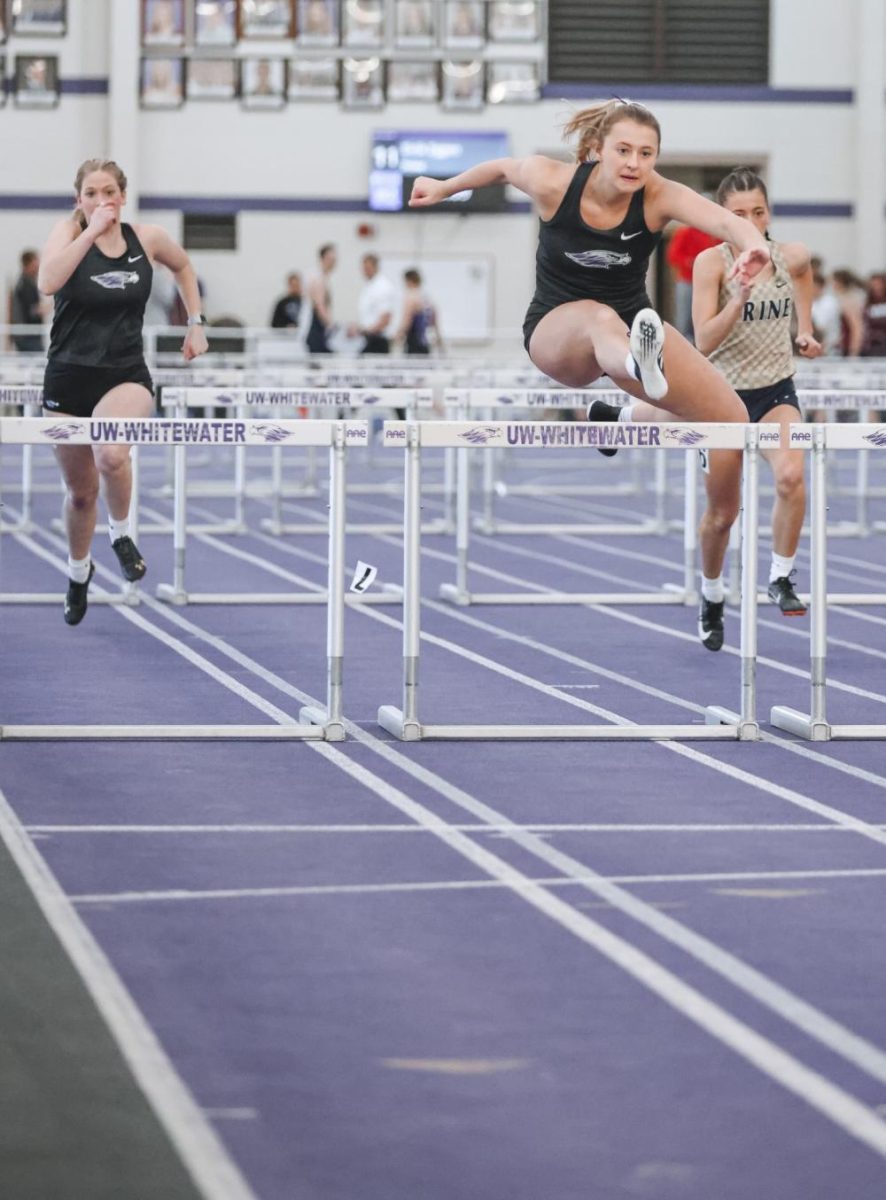 Morgan Amend (center) leaps over a hurdle during a meet in the Kachel Fieldhouse.