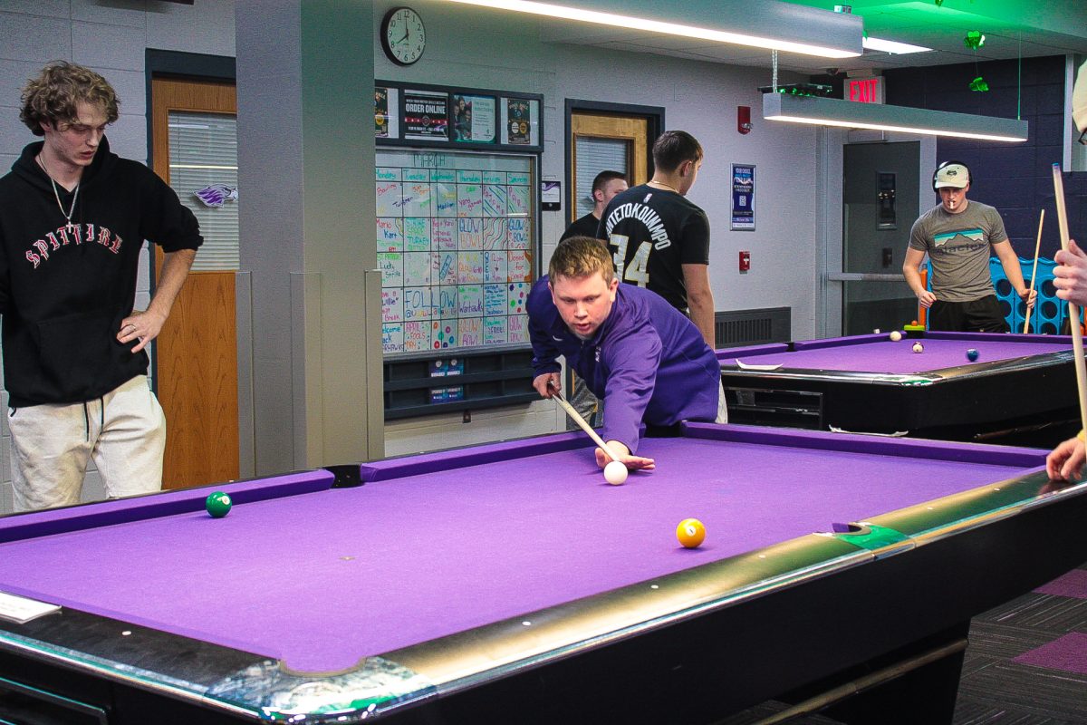 Patrick Nelson is preparing his shot on the Billiards Table in the Warhawk Alley.