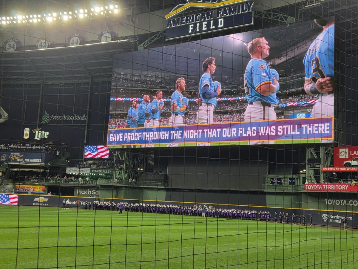 Marching Band plays the national anthem under the jumbotron as the Brewer players are shown on the screen paying tribute to the flag.