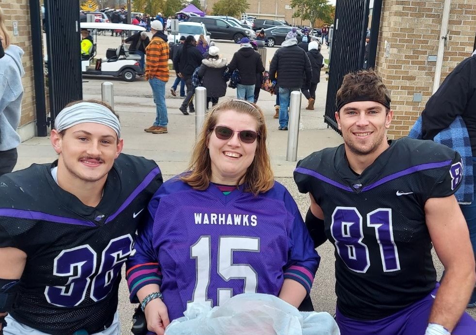 Warhawk football players smile for a photo with Katie Gruber, who loved cheering for her team at home games.