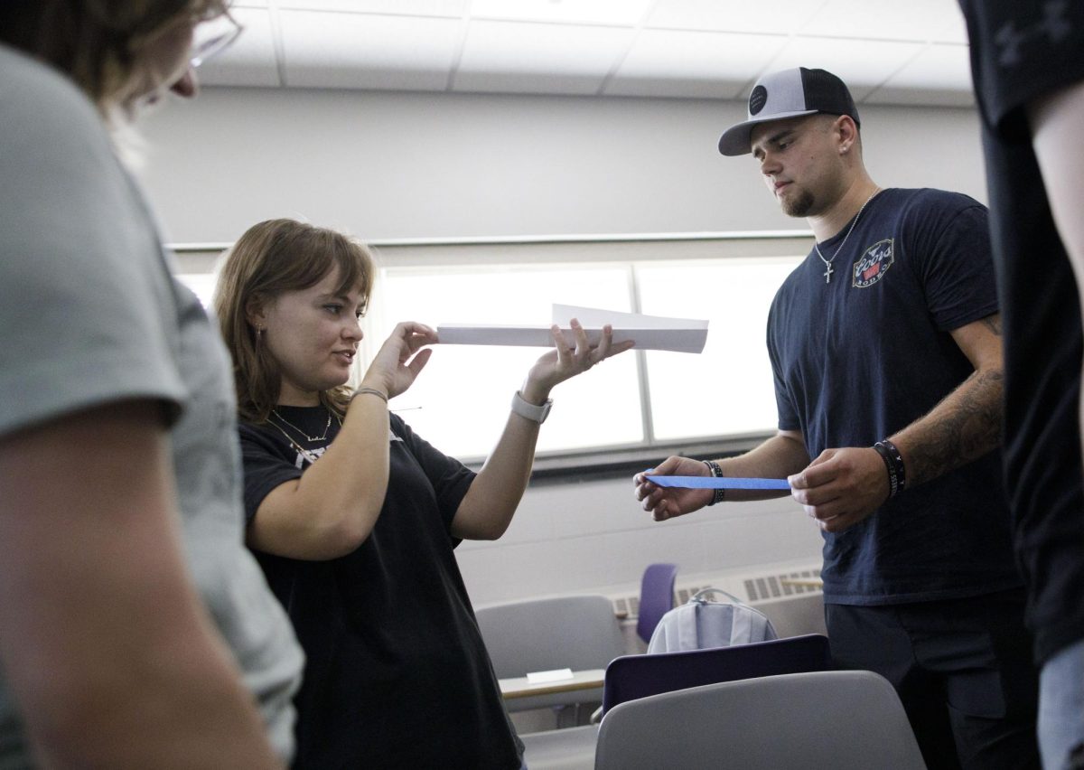 Kaelen Smith, left, an art major, and Logan Martinson, a communication major, work with their team on bridge-building. Students in Communication 328, a class taught by Assistant Professor Courtney Powers, worked on a team-building classroom exercise on Tuesday, Sept. 17, 2024, using paper, string, tape and lengths of dried spaghetti to devise and build bridges to support weight placed on them. (Craig Schreiner)
