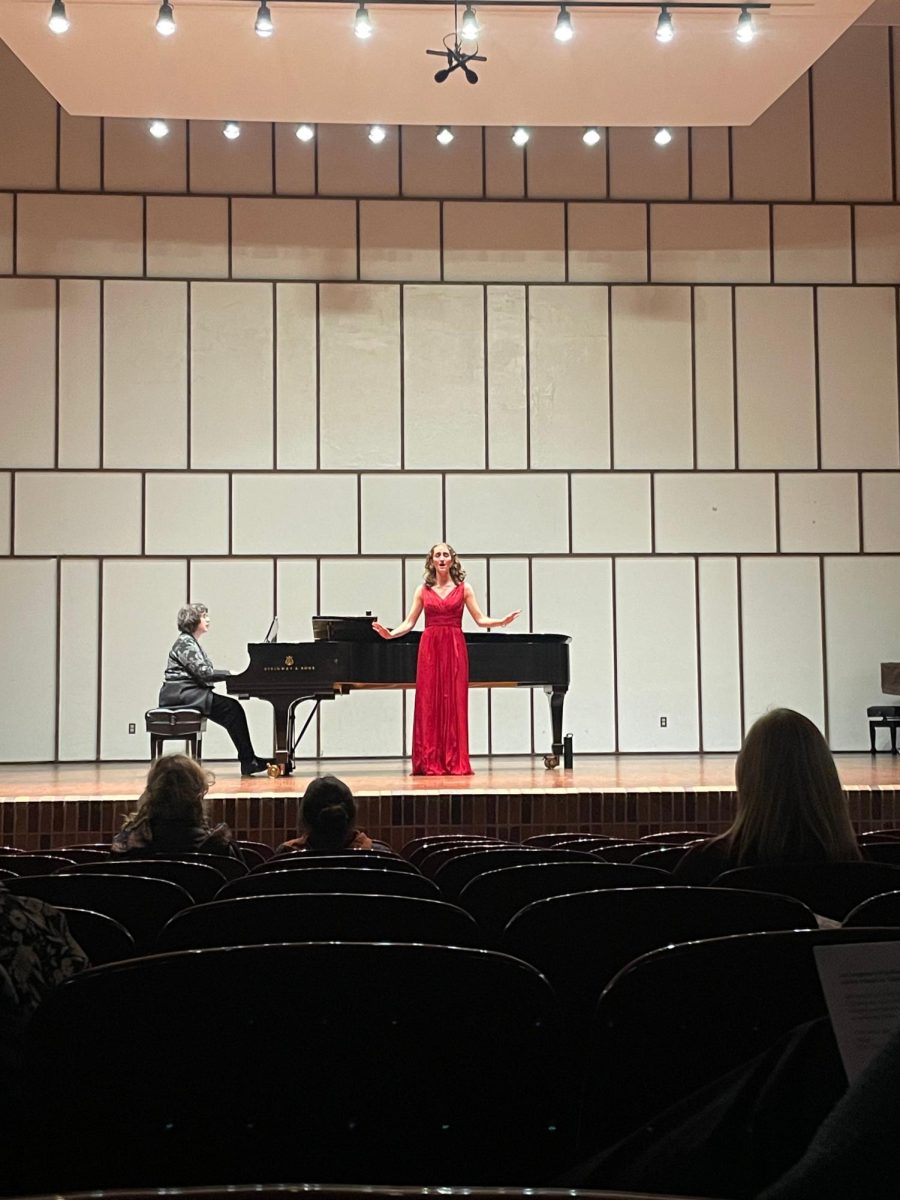 Emma Clark performing on stage in the light recital hall in her senior racial.
