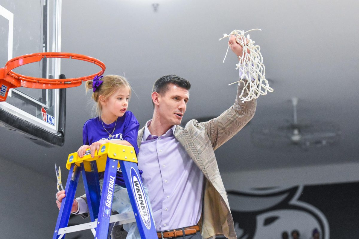 The UW-Whitewater Men’s Basketball coach Jarod Wichser and his daughter hold the net high after the cutting ceremony after the win against UW-River Falls, Feb. 21, 2026 in the Kachel Gymnasium. 