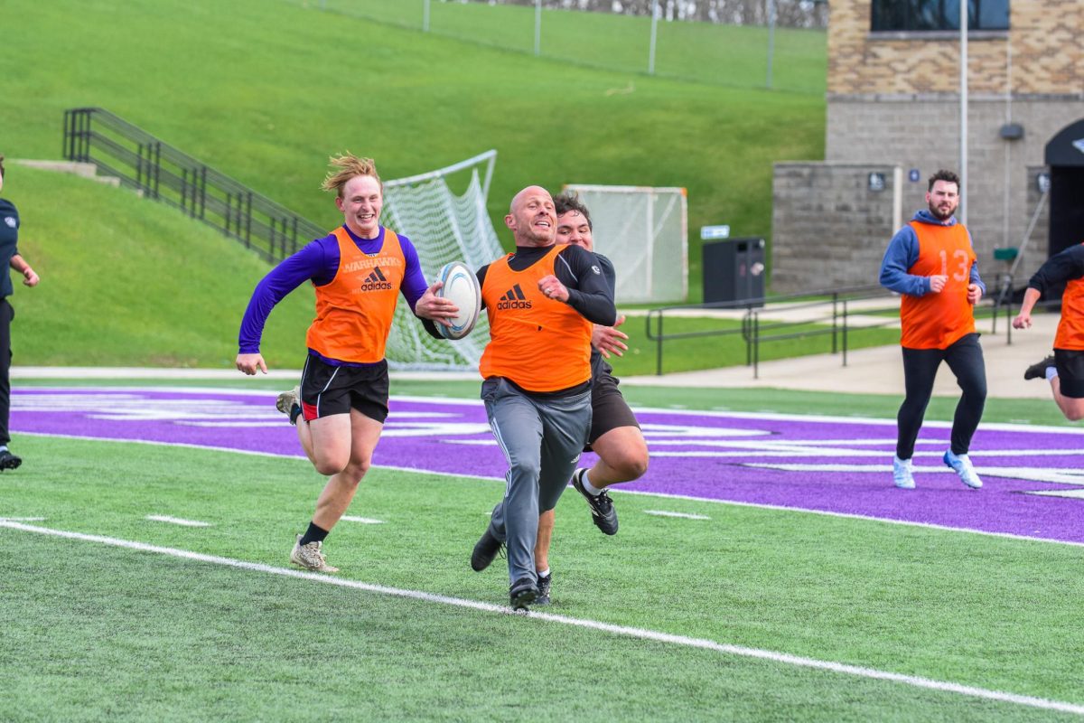UW-Whitewater Men’s Club Rugby alumni and current members run across the field as they laugh with one another during the annual rugby alumni match at Perkins Stadium, April 18, 2026. 
